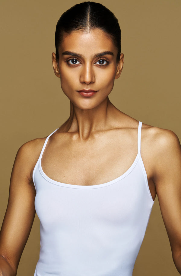 Woman wearing a white tank top against a beige background