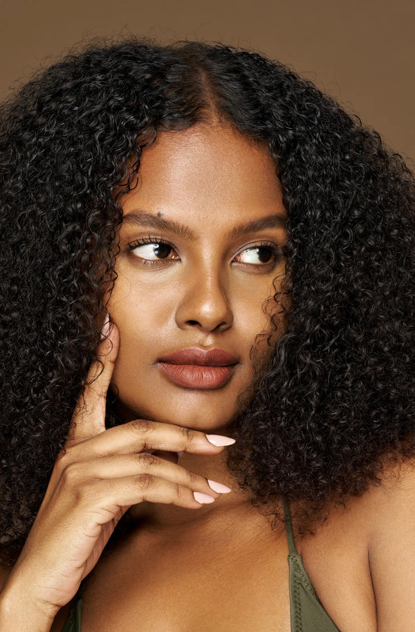 Woman with curly hair touching her face